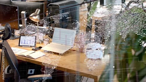 Camera panning across glass partition, dotted world-map shifting, revealing laptop, tablet, headset