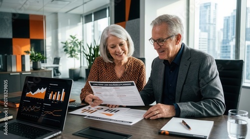 Senior Couple Reviews Financial Documents Together In Modern Office