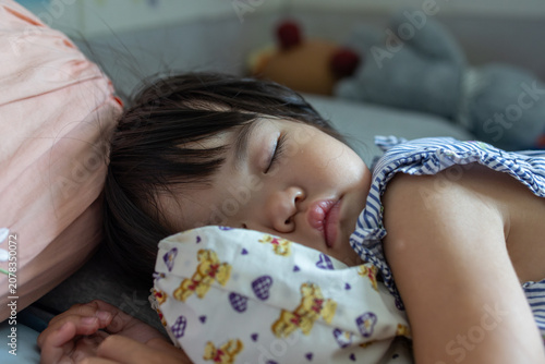Fotografía Close-up portrait of a sleeping Asian toddler girl resting peacefully in bed with a printed bolster pillow
