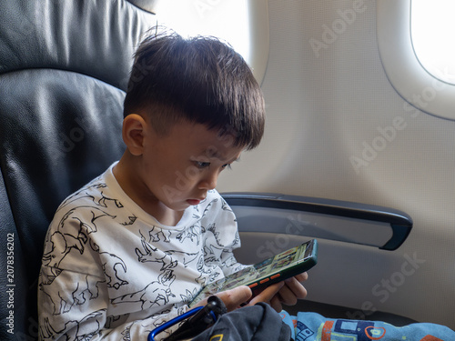 Cuadro en lienzo Young boy engrossed in a smartphone while seated on an airplane.