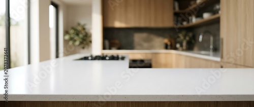 Empty white kitchen countertop with blurred modern wooden cabinet background