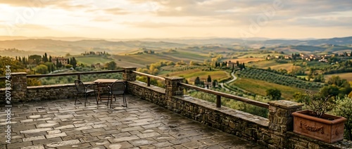 Scenic stone terrace with table and chairs overlooking sunset landscape in Tuscany Italy