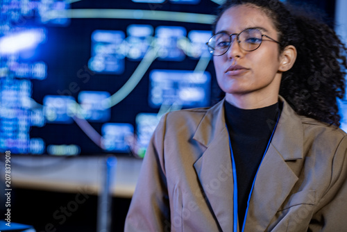 Konstfotografi An analyst manipulates data on a futuristic touchscreen showing a luminous rotating sphere in a dark control room, in a modern startup office after working hours