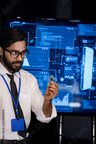 фотографія An engineer interacts with a futuristic touchscreen interface glowing with data in a bright modern laboratory, in a quiet, modern blue lit technology workspace amid the soft hum of a busy