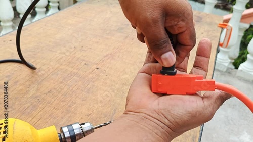 Hand plugging a drill electrical plug into an extension cord wire