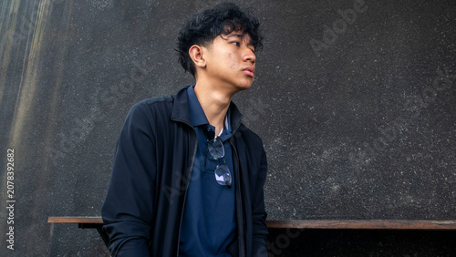 Foto young man wearing black jacket sitting against black wall
