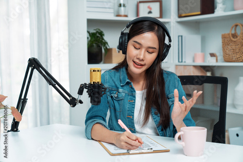 Foto Host channel of young beautiful Asian wearing jeans creative broadcaster talking in online broadcast explaining to promote marketing or consultant in daily life with listener at studio