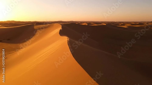 Golden hour desert sand dunes aerial view, vast sahara landscape at sunset