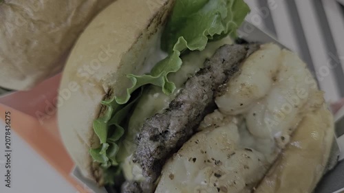 A video of a burger with shrimp and meat patties