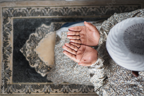 Fotografia Muslim man prays with hands open in a mosque setting