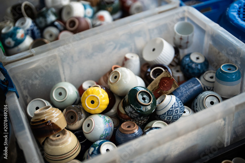 Tableau sur toile Recycle and reuse old tableware, pile of ceramic mugs reproduced as pots for pla