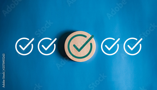 Large green check mark on wooden block among white icons on blue background