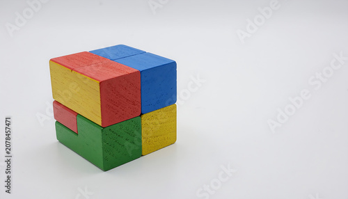 Colorful Wooden Block Cube with Red, Yellow, Blue, and Green Sections on White Background Representing Puzzle, Playful Design, and Educational Learning Through Shapes and Colors.