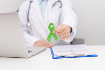 Doctor give lime Green Ribbon for concept of May Celiac Awareness month, Lyme disease, September Lymphoma, Mental Health Awareness month and October Liver cancer. Health and world cancer day