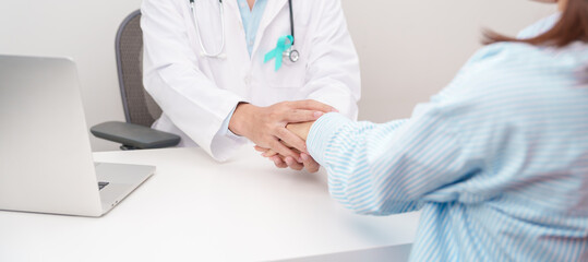doctor holding patient hand to comfort and support with empathy. Teal ribbon concept of September Ovarian Cancer Awareness month, PCOS, January Cervical Cancer, April Sexual Assault, June PSTD