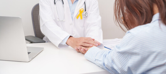doctor holding patient hand to comfort and support with empathy for Yellow Ribbon concept of yellow September, Suicide prevention day, Childhood, July Sarcoma, bone and bladder cancer Awareness month