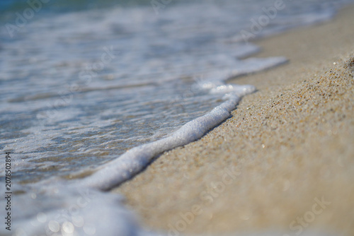 Macro view of white sea foam washing onto quartz sand beach of Is Arutas in Sardinia, Italy