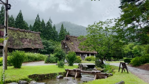 Slow panning view of Shirakawa-go traditional village on a rainy summer day with misty mountains, Japan