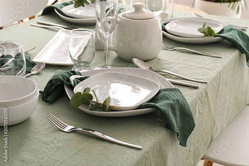Foto Elegant dining table set with white dishes and green napkins