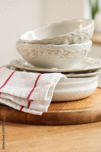 Billede på lærred Stack of ceramic bowls and plates with kitchen towel on wooden board