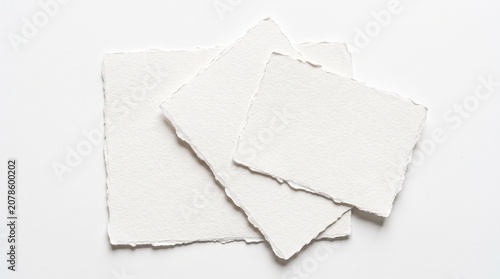 Handmade white paper with deckled edges, a stack of three textured artisan paper sheets, perfect for elegant stationery and craft projects