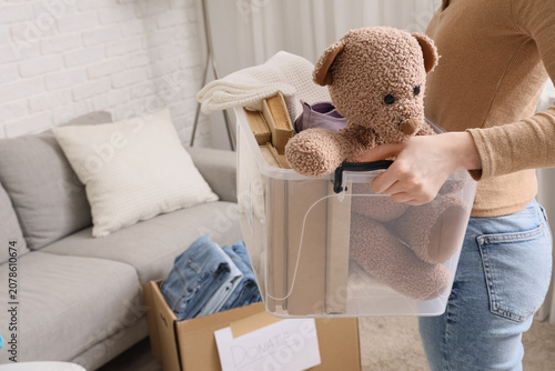 Foto Person holding donation box with teddy bear and books