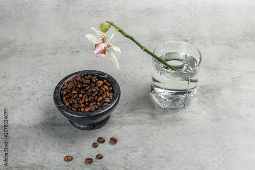 Stone bowl with roasted coffee beans and an orchid flower.