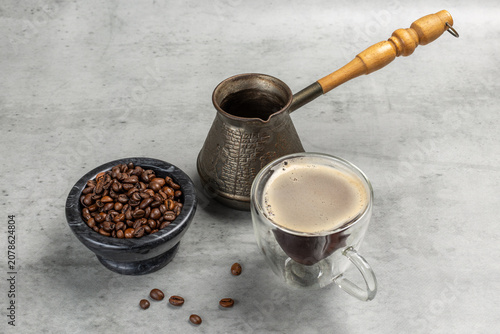 Stone bowl with roasted coffee beans, a cup of coffee and a cezve.
