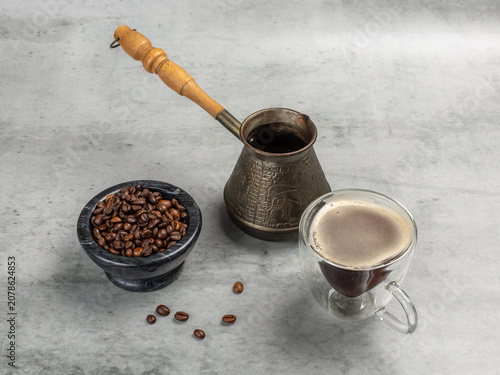 Stone bowl with roasted coffee beans, a cup of coffee and a cezve.