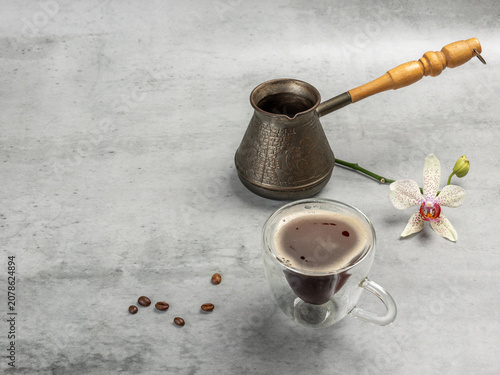 Cup of coffee, a cezve and an orchid flower.
