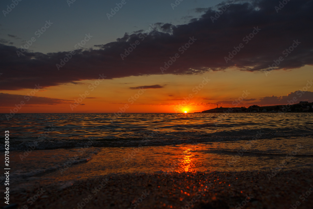 Obraz premium Orange Sunset Over the Sea With a Sandy Beach in the Foreground