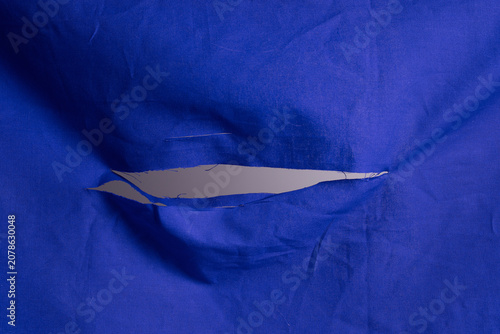 Fotografie Shredded hole at center of a red cloth, slit cut in a fabric texture
