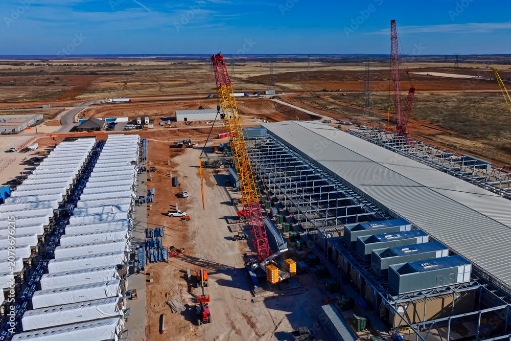 Obraz premium Aerial view of data center construction with BESS batteries and red cranes