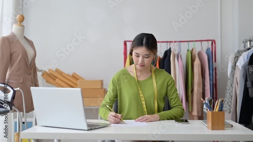 Asian female fashion designer sketching new clothes collection