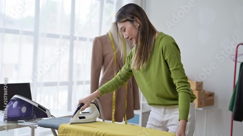 Fashion designer ironing yellow garment in bright studio