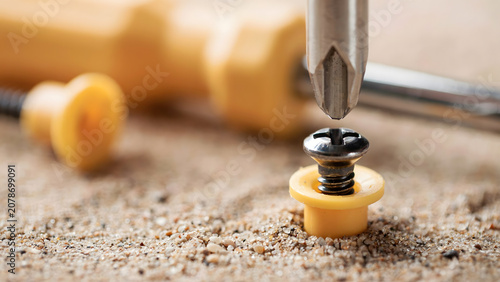 A Phillips head screwdriver tightening a small metal screw into wood