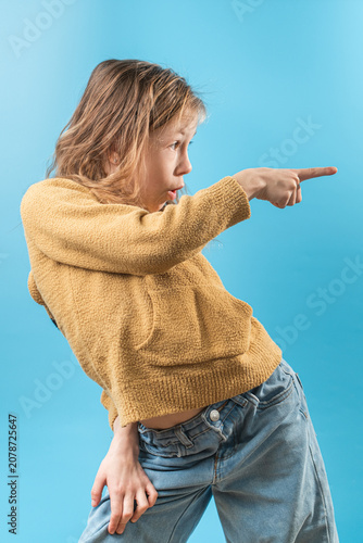 Cute stylish caucasian girl against blue background. Portrait of toddler girl in a yellow sweater for advertising poster.