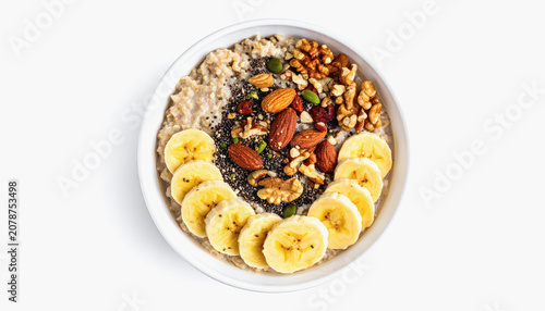 Overhead view of a healthy oatmeal bowl topped with sliced bananas, walnuts, almonds, chia seeds, and dried cranberries