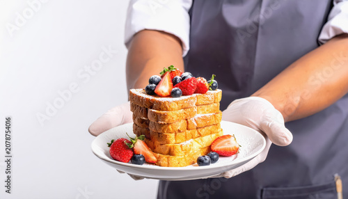 Stack of French Toast with Berries and Powdered Sugar Served on a Plate