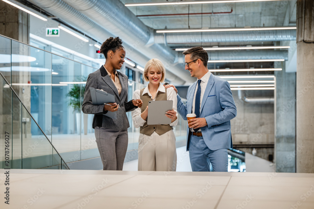 Fototapeta premium Business colleagues discussing project on tablet in modern office — Black and Caucasian professionals