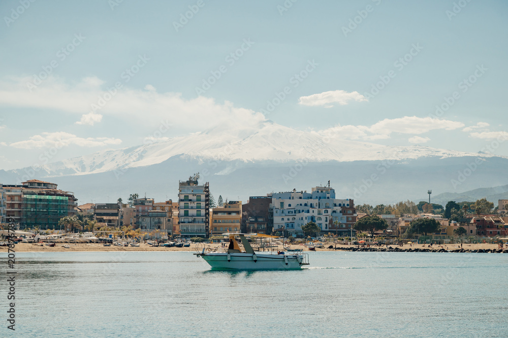 Obraz premium Boat sailing by Giardini Naxos coast and Mount Etna