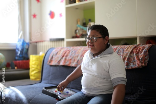 Photography Young boy with glasses plays a game on the couch