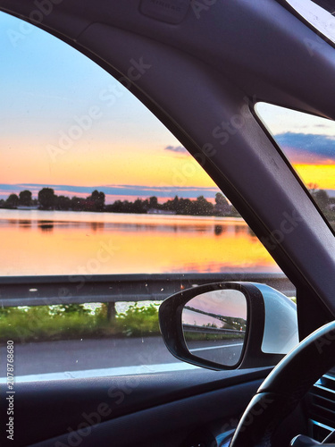 View from car window during summer car travel at sunset  