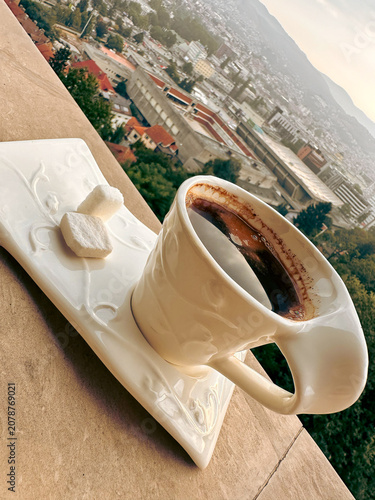 Coffee cup with sugar on saucer overlooking cityscape in the morning  
