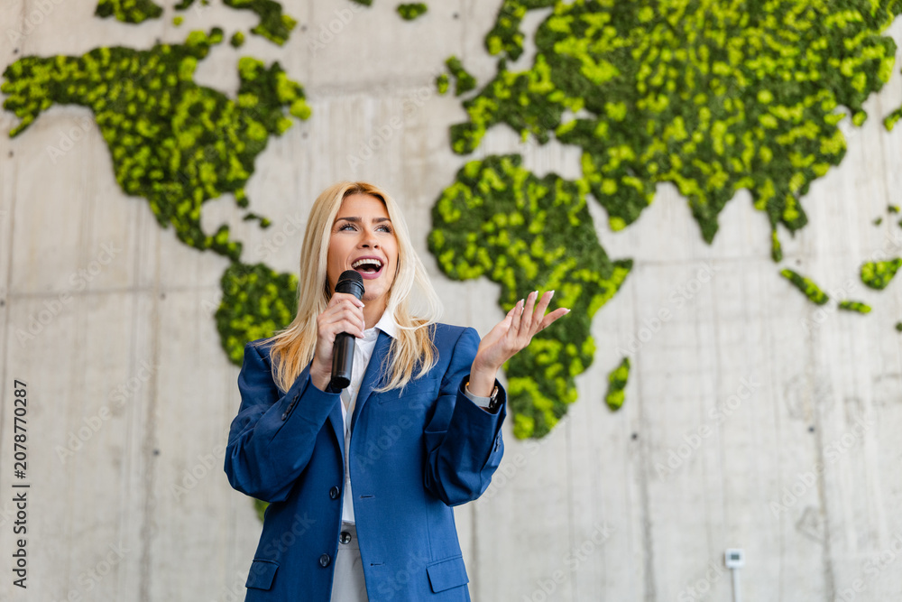 Fototapeta premium Business speaker presenting sustainable global strategy in front of living world map, Caucasian American woman