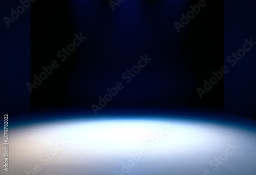 A spotlight shines brightly on a dark empty stage floor suddenly