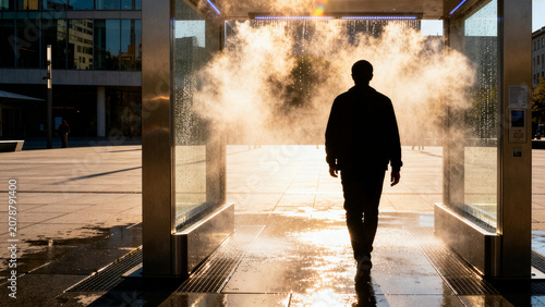 Public water misting cooling station in modern city square during summer heatwave.