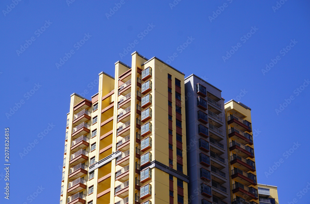 Fototapeta premium Modern High-Rise Residential Apartment Building Under Clear Blue Sky