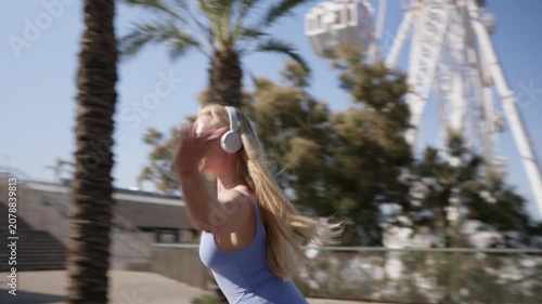 Blonde woman rollerblading and listening to music outdoors