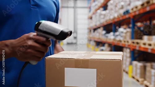 Warehouse worker scanning barcode on cardboard box with laser